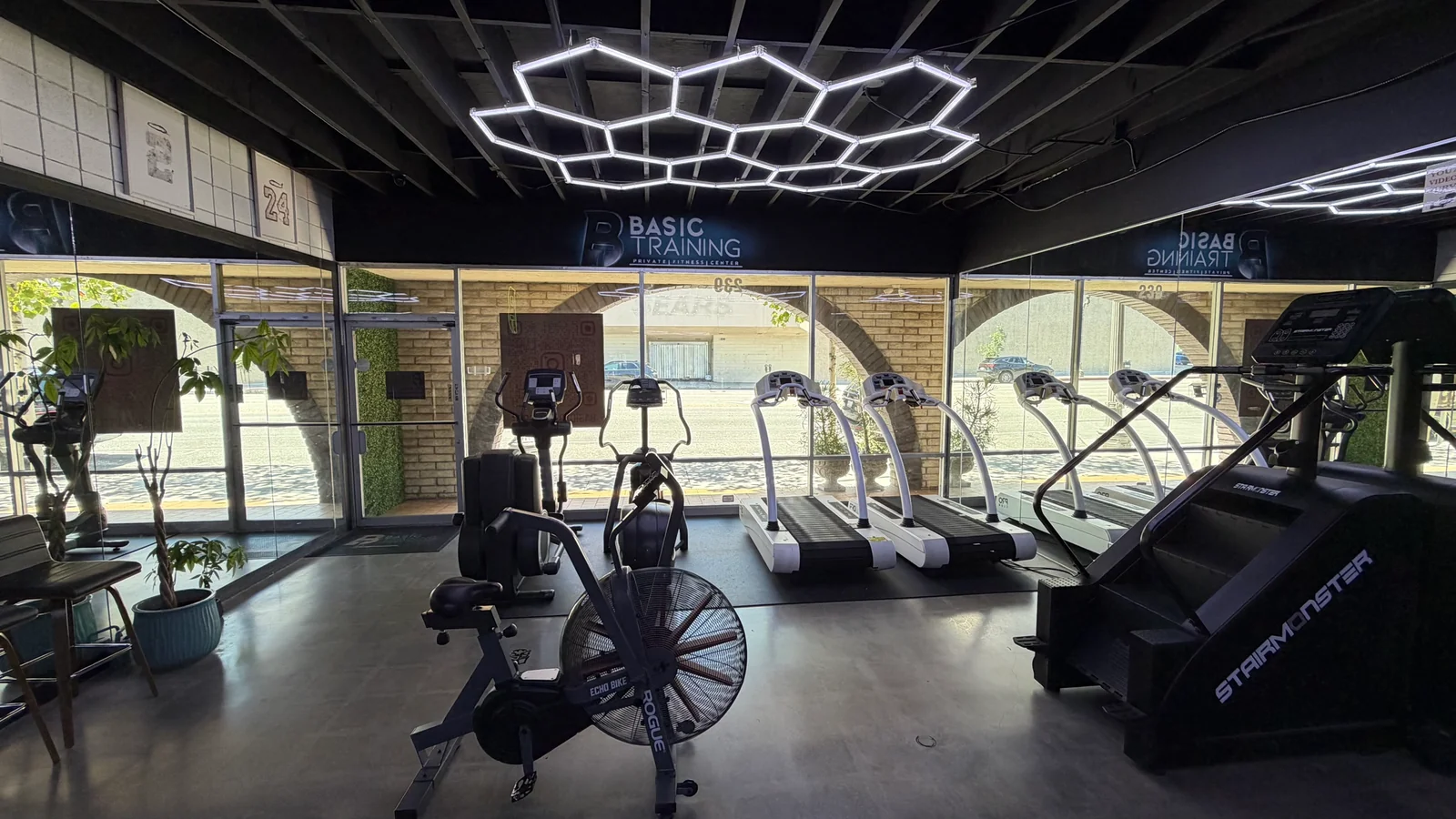 Treadmills, ellipticals, fan bike and stair climber beside the storefront windows at BASIC Training