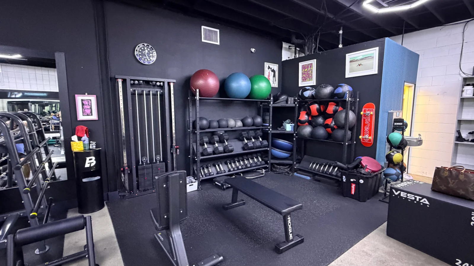 Stability balls, medicine balls and dumbbell racks beside framed artwork at BASIC Training