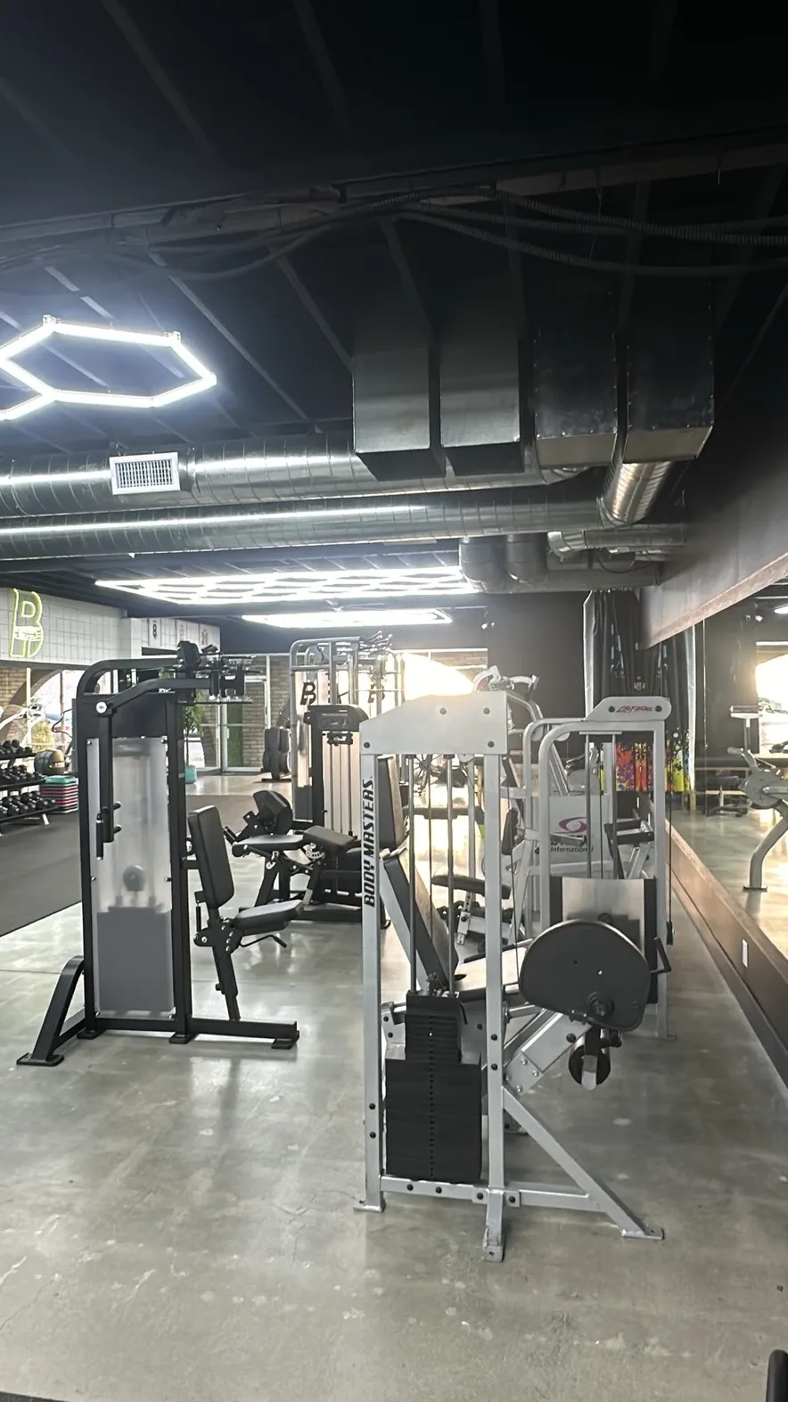 Row of selectorized strength machines on polished concrete at BASIC Training studio